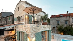 A stone building with a balcony, a pool, and outdoor furniture. - Villa Mara Casa Rustica ZadarVillas (Korcula)