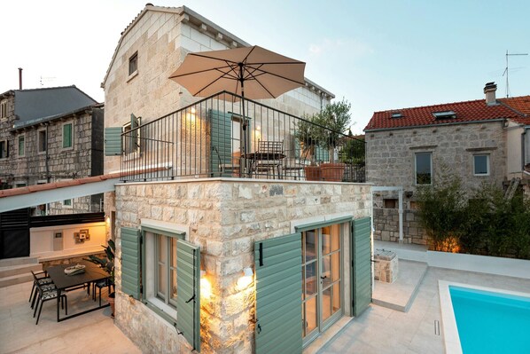 A stone building with a balcony, a pool, and outdoor furniture. - Villa Mara Casa Rustica ZadarVillas (Korcula)