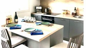 Una cocina moderna con armarios oscuros, una isla central con asientos y una cafetera.