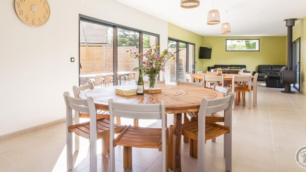 A spacious dining area with a round wooden table, white chairs, and a clock on the wall. - Spacious house with heated pool and pets allowed (Vesly)
