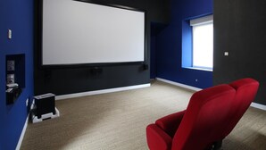 A home theater room with a large screen, a red chair, and a carpeted floor. - Spacious house with heated pool and pets allowed (Vesly)