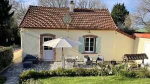 Ein Haus mit einem Ziegeldach, einer Veranda mit Gartenmöbeln und einem Garten.