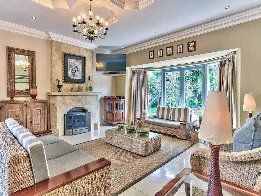 A spacious living room with a fireplace, comfortable seating, and a large window offering a view of greenery.