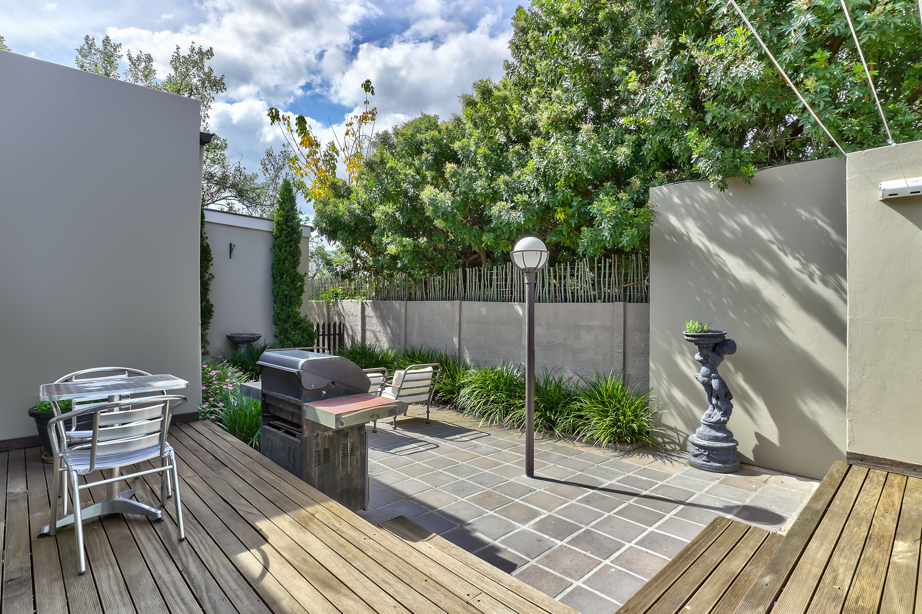 A patio with a grill, a metal table, and chairs.