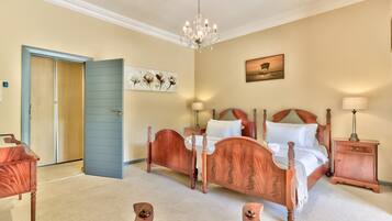 A bedroom with a wooden four-poster bed, a chandelier, a nightstand, and a door with a blue frame.