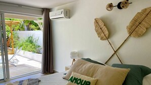 Una camera da letto con un letto, un cuscino con la scritta "AMOUR", un condizionatore d'aria e vista sull'esterno.