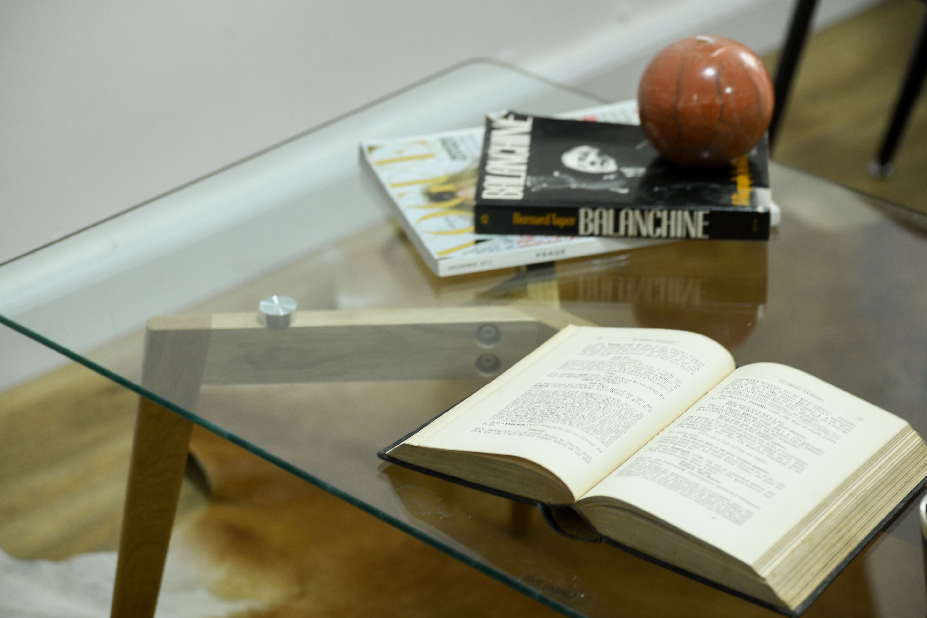 A glass table with a book, a magazine, and a basketball.