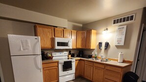 A compact kitchen with wooden cabinets, a white refrigerator, a microwave, and a stove.