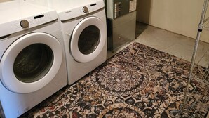 A laundry area with two white front-loading washing machines and a large gray utility meter.