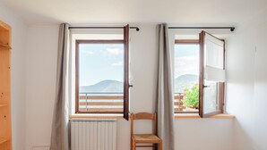 Ein Zimmer mit Holzboden, einem Fenster mit Bergblick, einem Heizkörper und einem Sessel.