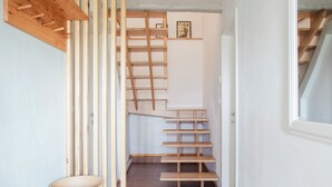 Ein schmaler Flur mit einer Holztreppe und einem Korb auf einem Holztisch.