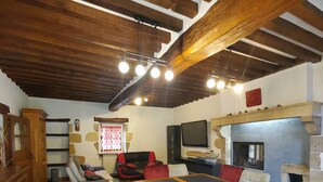 Un comedor rústico con una mesa de madera, sillas coloridas, una chimenea de piedra y una pared de piedra.
