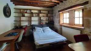 Una habitación acogedora con cama, escritorio y estantería.