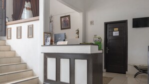 Ein Empfangstresen mit einem Schild, eine Treppe, eine Tür mit der Aufschrift '101' und ein Fernseher an der Wand.