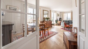 Ein geräumiges Wohnzimmer mit Essbereich, großen Fenstern und einem Kamin.