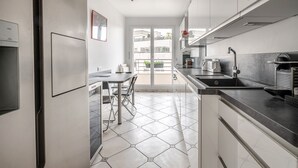 Eine moderne Küche mit Essbereich, einem Kühlschrank, einer Spüle und einem Fenster mit Blick auf einen Balkon.