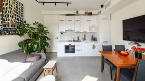 Eine moderne Küche mit weißen Schränken, einem eingebauten Backofen und einem Essbereich mit einem Holztisch und Stühlen.