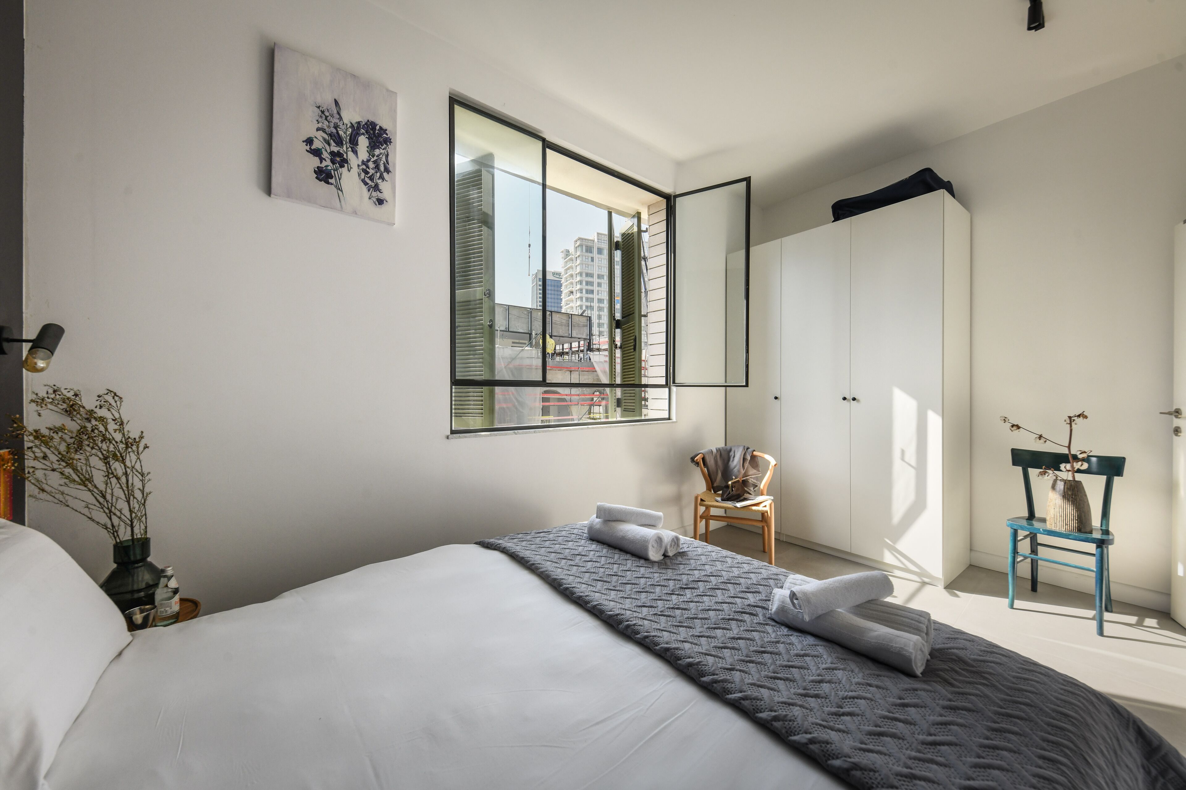 Ein modernes Schlafzimmer mit einem großen Bett, einem Spiegel, einem Sessel und einem Kleiderschrank.