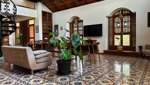 A spacious living area with a patterned floor, a sofa, a dining table, chairs, and large green plants. - Mae Terra An Island Pool Villa By Jade (Chorao)