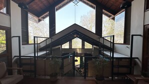 A spacious interior with a high ceiling, large windows, and a central staircase. - Mae Terra An Island Pool Villa By Jade (Chorao)