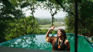 A person standing on a balcony with a view of a river and greenery. - Mae Terra An Island Pool Villa By Jade (Chorao)