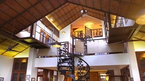 A multi-level interior with a central spiral staircase, wooden beams, and hanging lights. - Mae Terra An Island Pool Villa By Jade (Chorao)