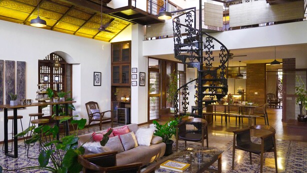 A spacious lobby with a high ceiling, a spiral staircase, and a seating area with a sofa and chairs. - Mae Terra An Island Pool Villa By Jade (Chorao)