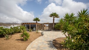 A stone pathway leading to a covered outdoor area with a view of the landscape. - Nur Mykonian Suites (Mykonos)