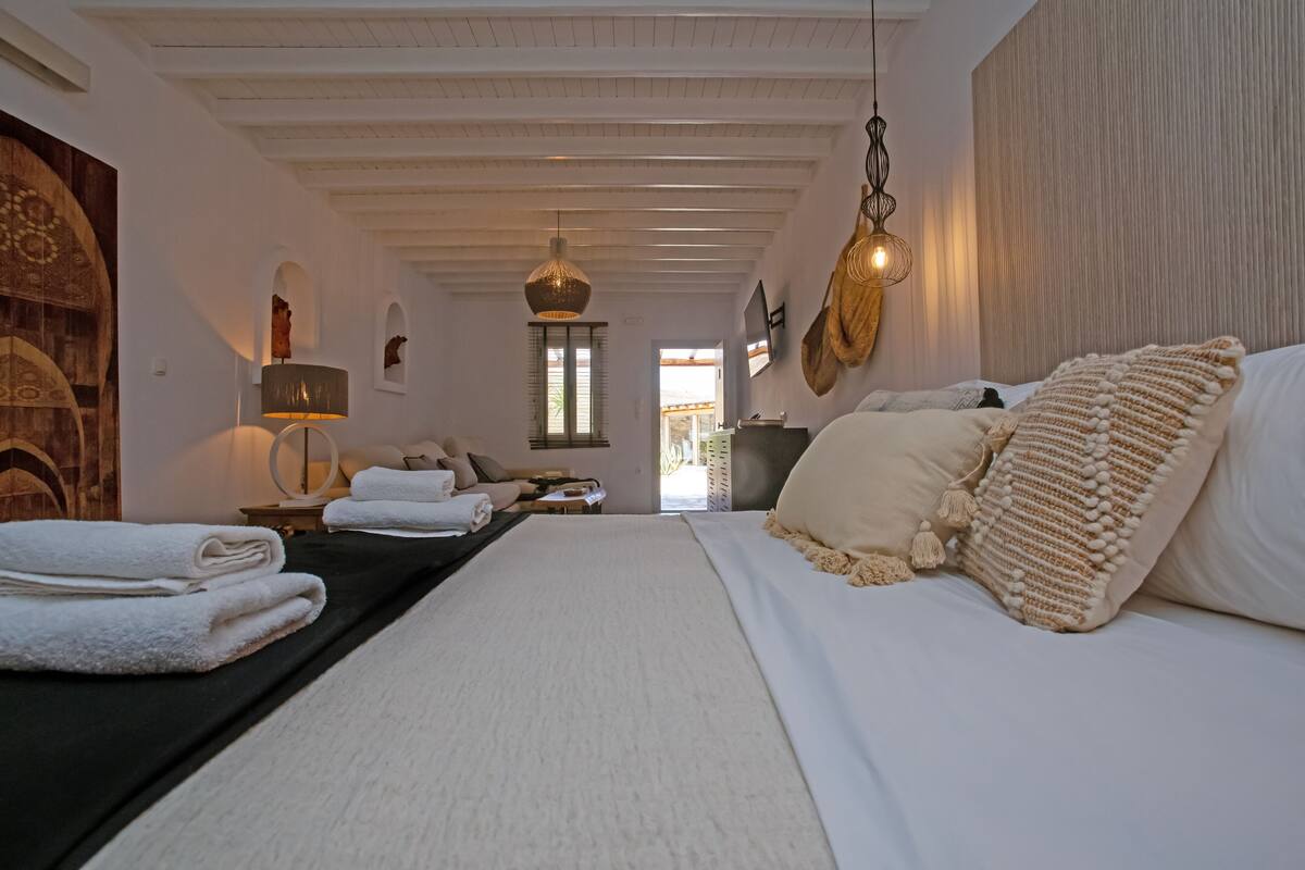 A spacious bedroom with a large bed, a black headboard, and a wooden wall decoration.