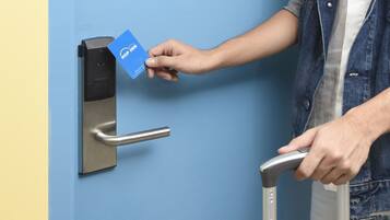 Una persona utilizando un lector de tarjetas para acceder a una puerta con picaporte metálico.