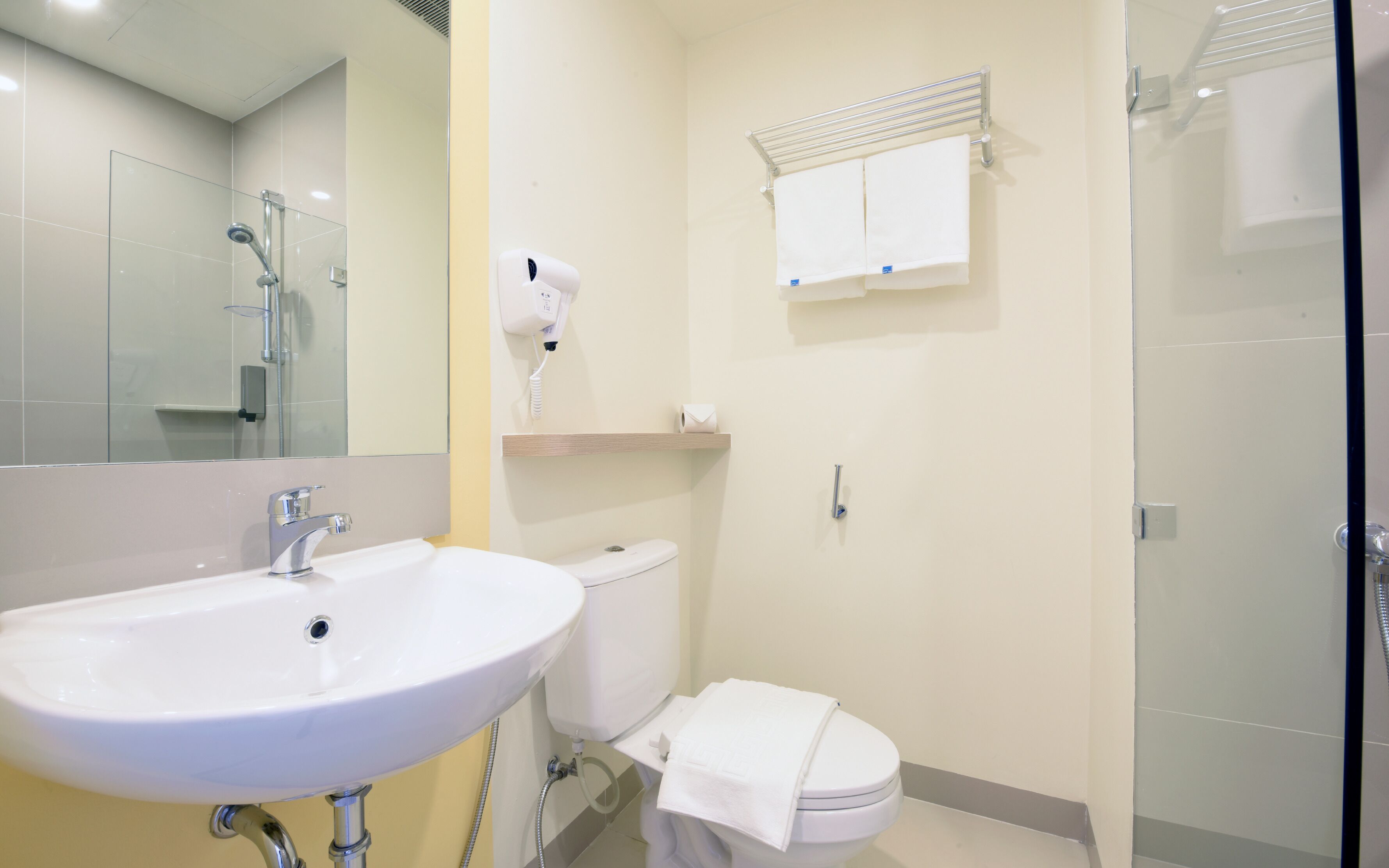 Et badeværelse med hvid vask, toilet og brusekabine i glas.