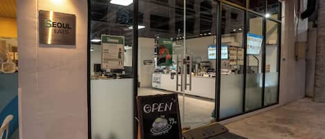 En restaurantindgang med et skilt, der viser "Seoul Eats", og en menutavle udenfor.