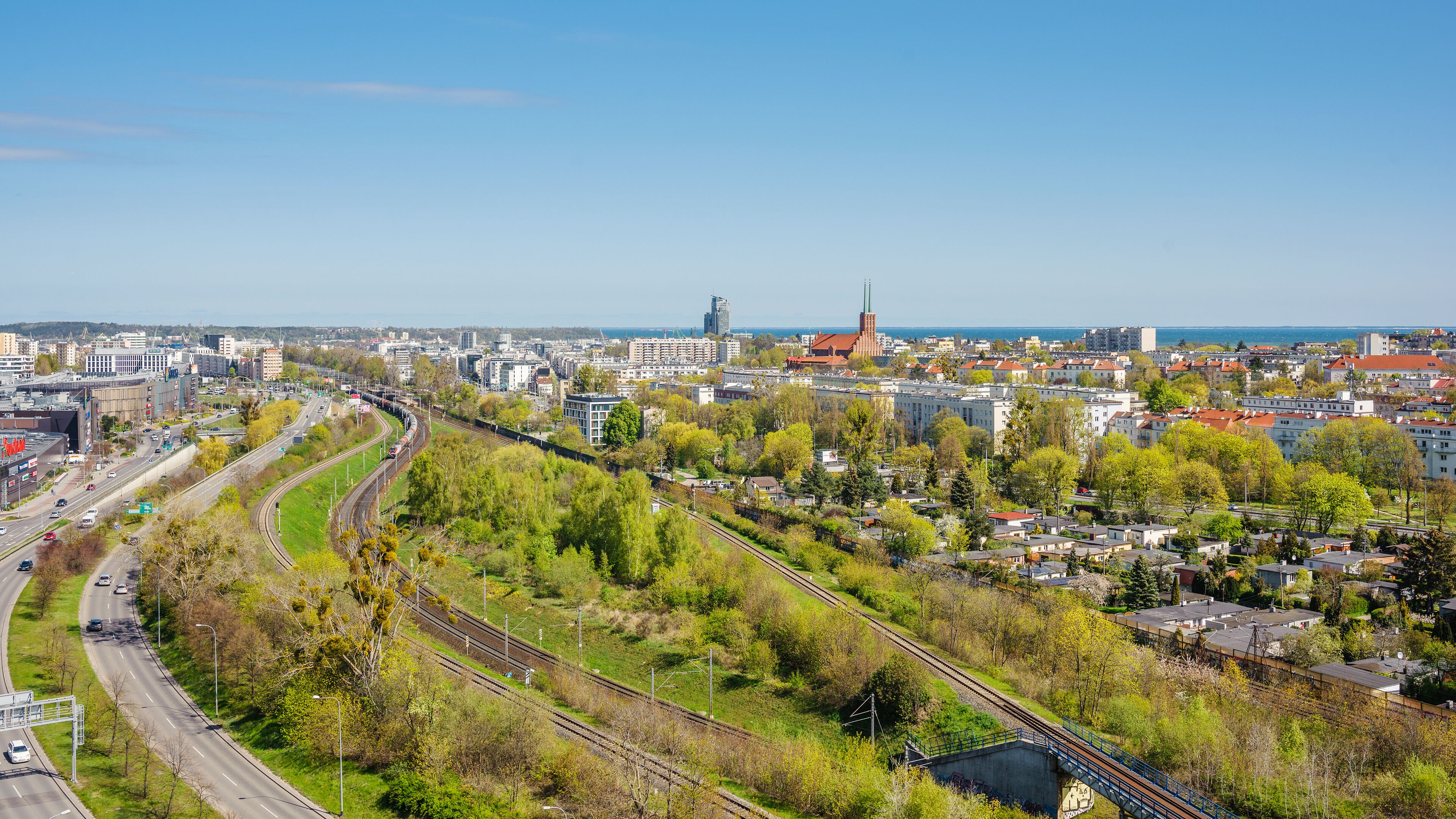 A cityscape with a prominent railway track curving through the center, surrounded by residential buildings and greenery.