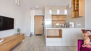 A modern kitchen with a central island, wooden cabinets, and pendant lighting. - Apartamenty Sun&Snow Modern Tower (Gdynia)