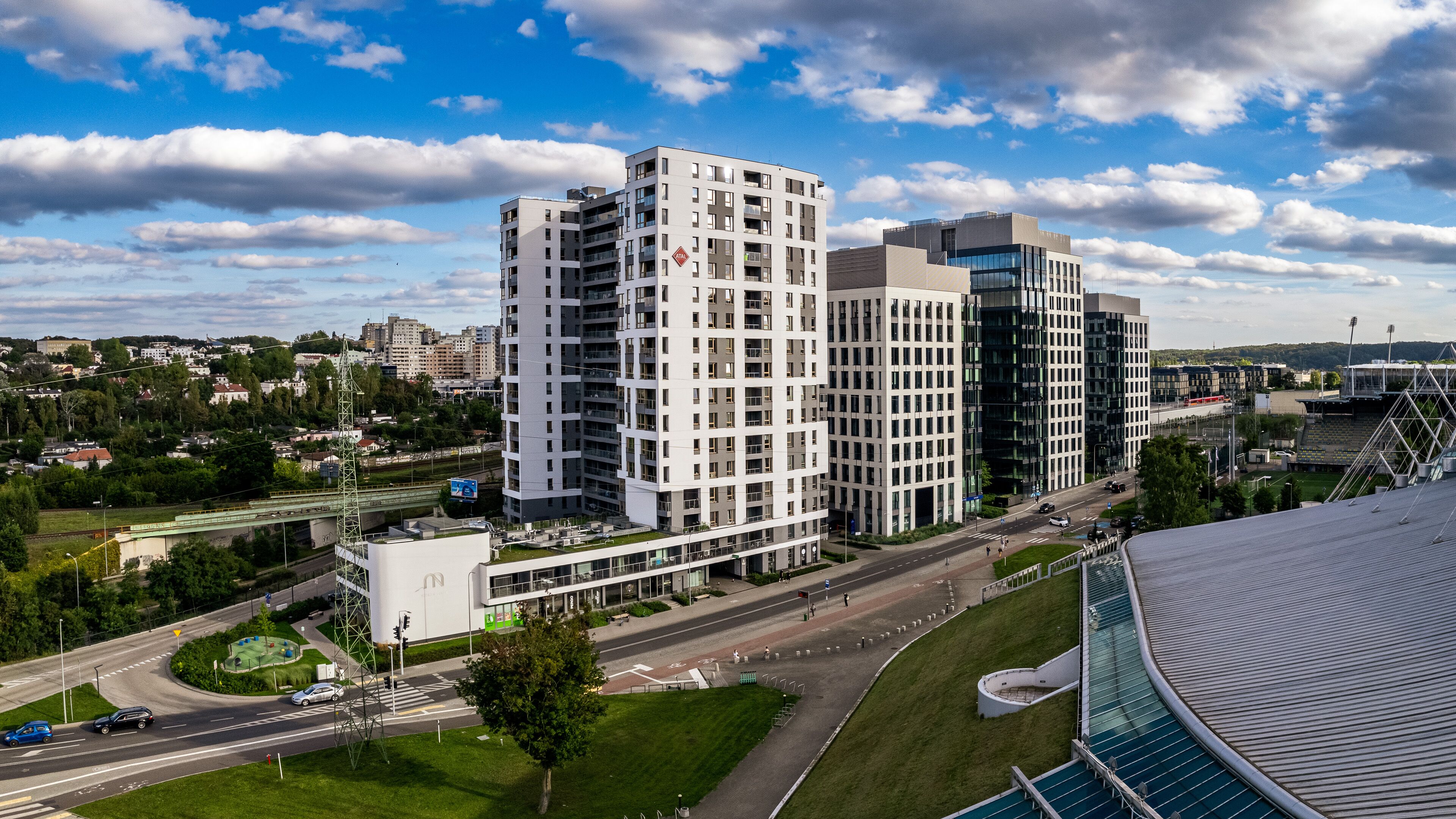 Un quartier urbain moderne avec de hauts immeubles, un stade et un pont.