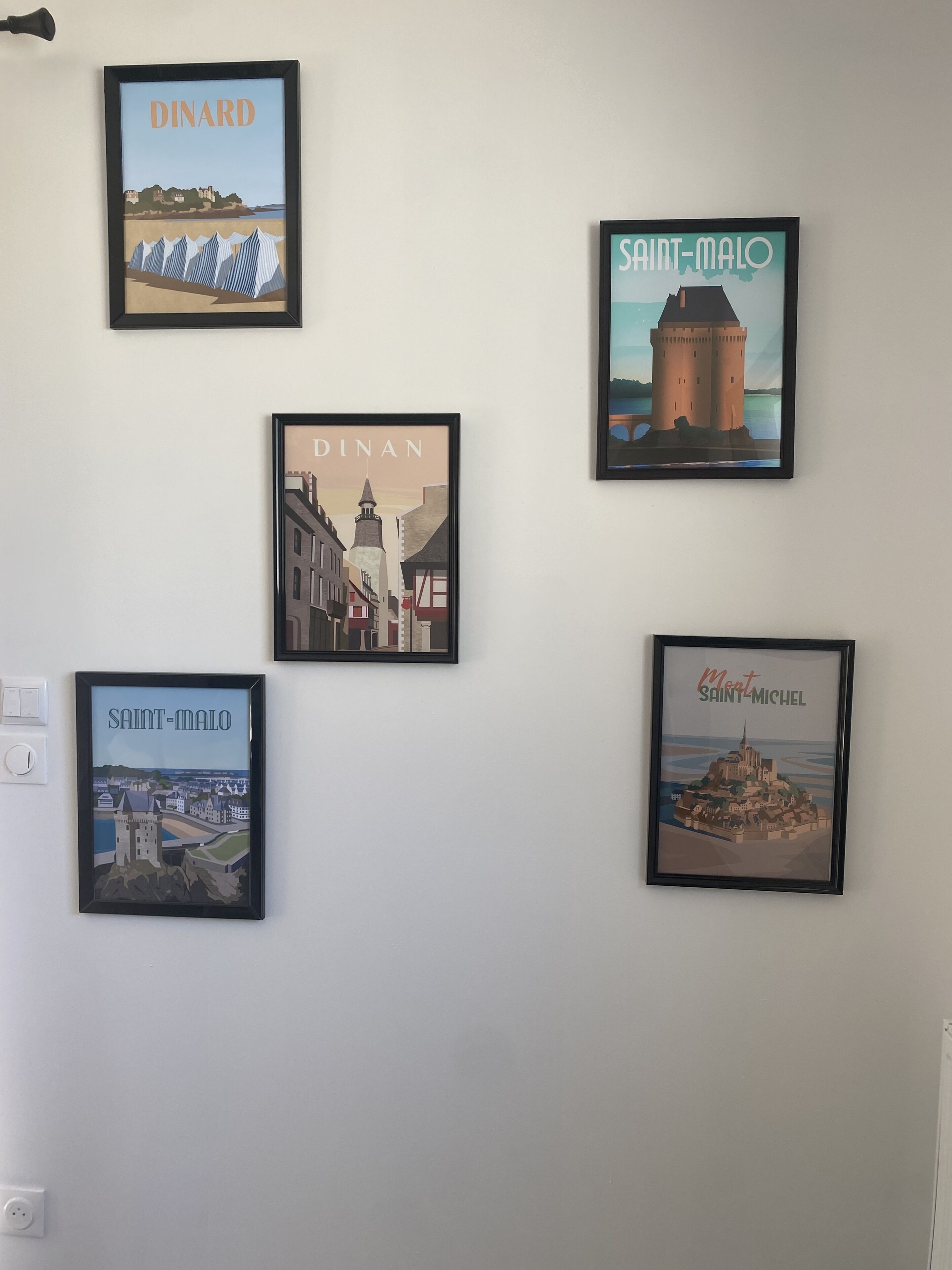 Four framed illustrations of European towns on a wall.