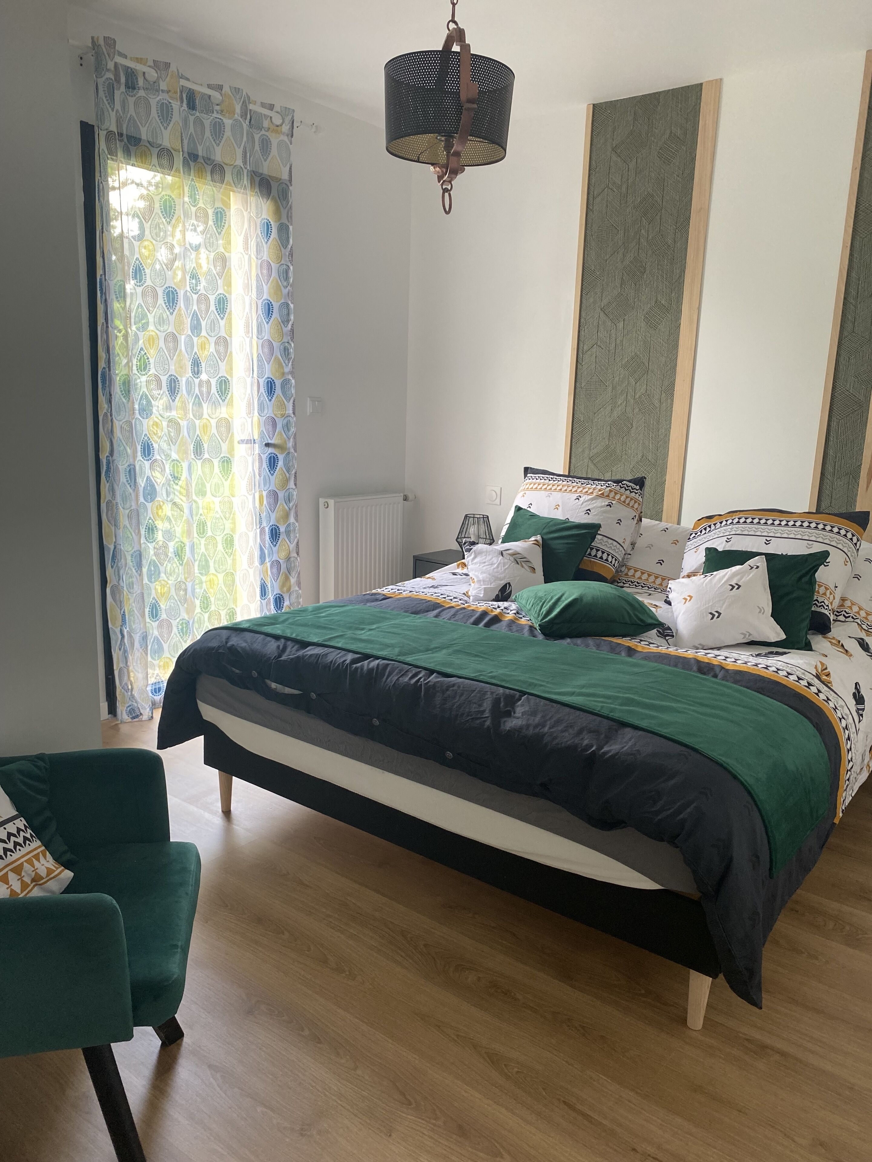 Een slaapkamer met een bed, een stoel, een hanglamp en een radiator.