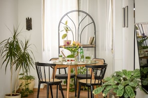 A dining area with a round table, black chairs, and potted plants.