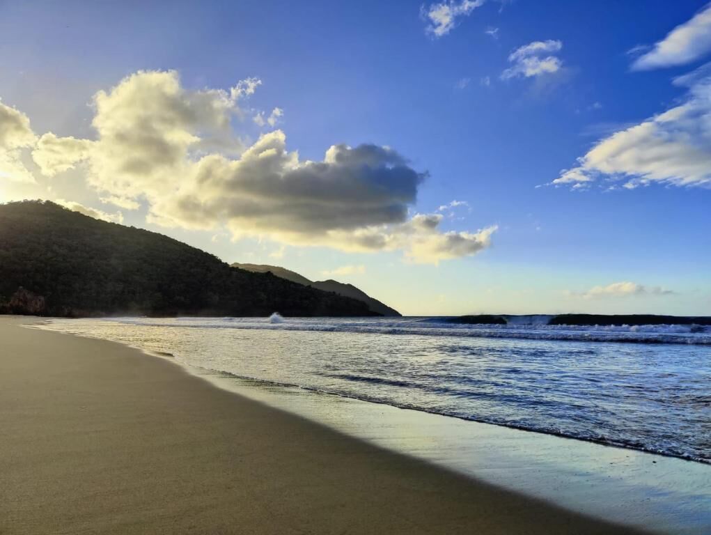 A beach with a clear sky and a mountain in the background.