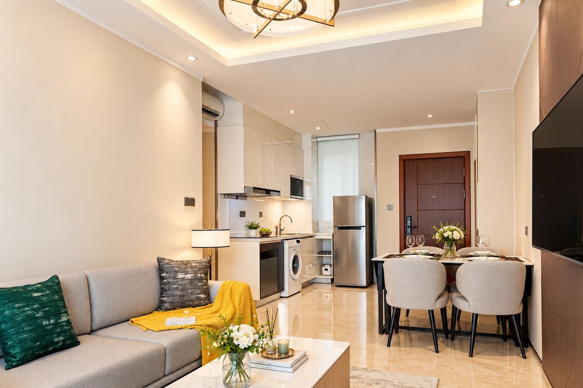 A modern living room with a sofa, coffee table, and a dining area with chairs and a table.