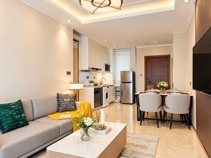 A modern living room with a sofa, coffee table, and a dining area with chairs and a table.