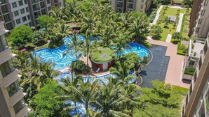A high-rise building with a rooftop pool surrounded by palm trees and greenery. - Soladia Hotel & Residences by One Park (Phnom Penh)