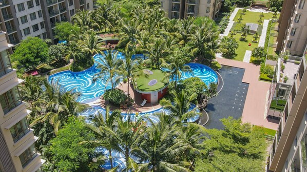 A high-rise building with a rooftop pool surrounded by palm trees and greenery. - Soladia Hotel & Residences by One Park (Phnom Penh)