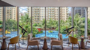 A hotel room with large windows, a pool view, and modern furniture. - Soladia Hotel & Residences by One Park (Phnom Penh)