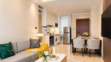 A modern living room with a sofa, coffee table, and a dining area with chairs and a table.
