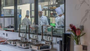A kitchen with chefs in white uniforms and hats, stainless steel appliances, and food service equipment.