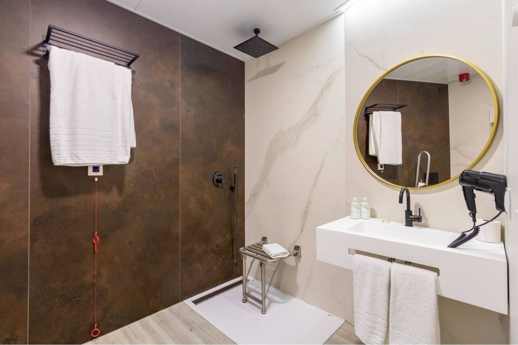 Une salle de bain moderne dotée d’une douche à l’italienne, d’un meuble-lavabo avec miroir et d’un sèche-cheveux.