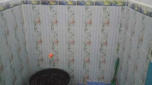 A small bathroom with a toilet, a bucket, and a mirror. - Hotel O Wisma Nadira Near SPBU PT. Trijaya Pugung PENENGAHAN (Pesisir Utara)