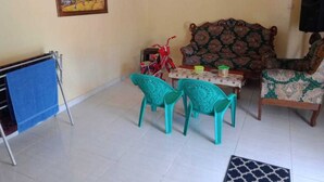 A living room with a sofa, two chairs, a small table, a red bicycle, and a painting on the wall. - Hotel O Wisma Nadira Near SPBU PT. Trijaya Pugung PENENGAHAN (Pesisir Utara)