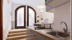 A modern kitchen with a built-in sink, a wooden countertop, and a staircase leading to a second floor. - Domus Luxury Suite  (Rome)